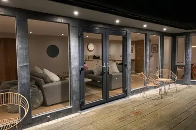 a living room with glass windows and a couch at Wilderness Lodge in Oswestry