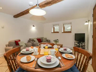 a dining room with a wooden table with food on it at Bluebell Cottage in Leominster