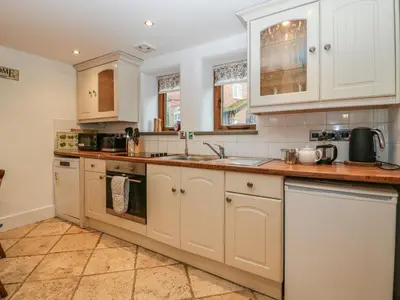 a kitchen with white cabinets and a sink at Bluebell Cottage in Leominster