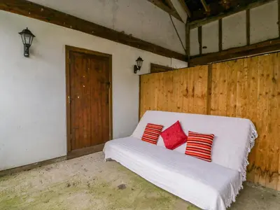 a white bed with red pillows in a room at Bluebell Cottage in Leominster