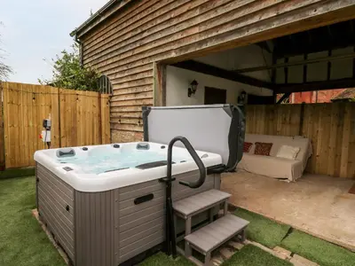 a jacuzzi tub in a yard next to a house at Bluebell Cottage in Leominster