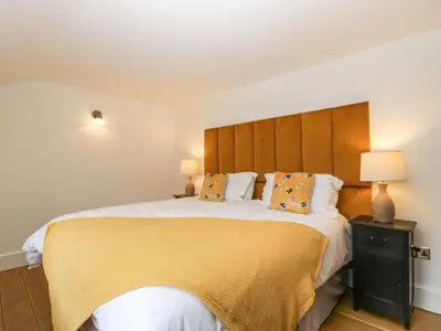 a bedroom with a large bed with yellow sheets and pillows at Beekeeper's Cottage in Leominster