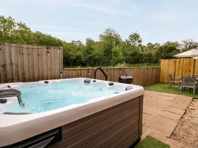a jacuzzi tub in a yard with a patio at Beekeeper's Cottage in Leominster