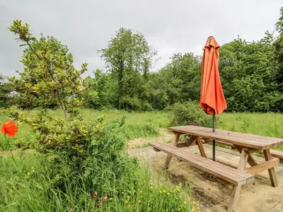 an orange umbrella sitting on a wooden picnic table at Beekeeper's Cottage in Leominster