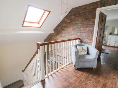 a living room with a chair and a brick wall at Tynewydd Fields in Lampeter