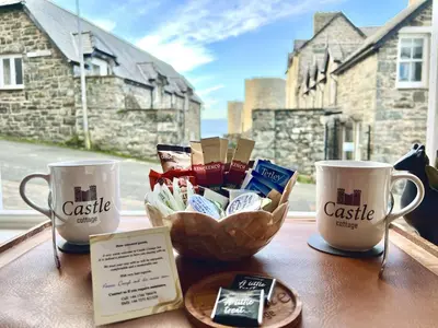 a table with two coffee cups and a bowl of cookies at Castle Cottage Inn in Harlech
