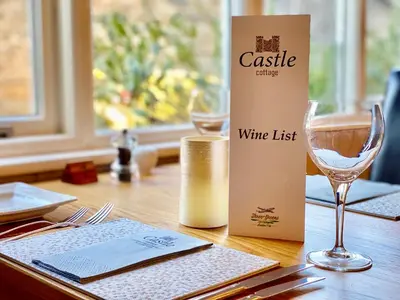 a table with a wine list and a wine glass at Castle Cottage Inn in Harlech