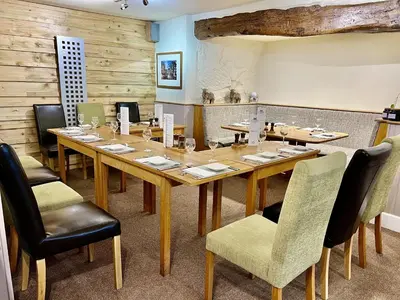 a dining room with a large wooden table and chairs at Castle Cottage Inn in Harlech