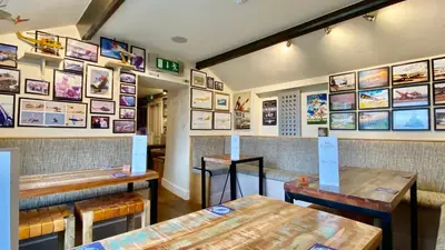 a restaurant with wooden tables and pictures on the wall at Castle Cottage Inn in Harlech