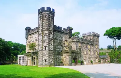 an old stone castle with a grass yard at Portmeirion Village & Castell Deudraeth in Porthmadog