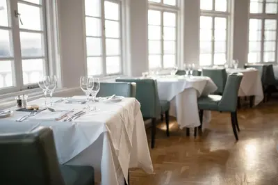 a dining room with white tables and green chairs at Portmeirion Village & Castell Deudraeth in Porthmadog