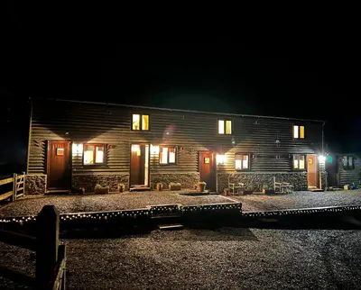 a wooden house at night with lights on it at The Calf Cotts in Pembridge