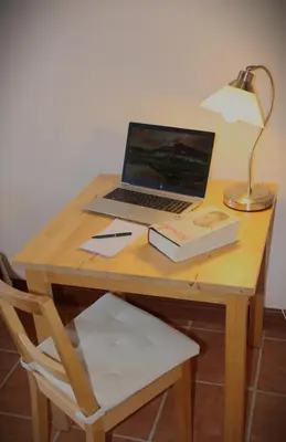 a laptop computer sitting on a wooden desk with a lamp at The Calf Cotts in Pembridge