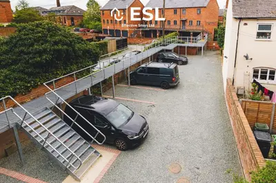 two cars parked in a parking lot next to a building at High Quality 2 Bedroom Church Apartment 5 Mins to Town Centre - Free Parking in Shrewsbury