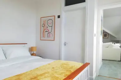 a white bedroom with a bed and a chair at Cosy, elegant apartment in heart of Ludlow Town in Ludlow
