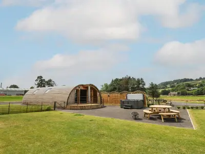 a wooden yurt with a picnic table and a grill at Buttercup in Rhayader