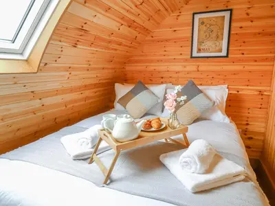 a bed in a log cabin with a tray of food at Bluebell in Rhayader