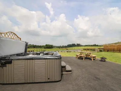 a hot tub on a patio with a picnic table at Bluebell in Rhayader