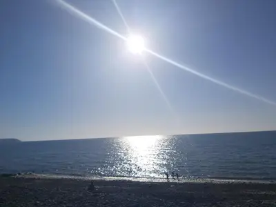 a beach with the sun shining on the water at Llys Bach Apartment at Llys Aeron in Aberaeron