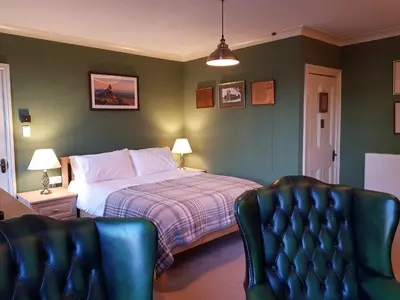a bedroom with a bed and two chairs at Afallon Townhouse in Dolgellau