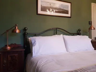 a bedroom with a bed with white sheets and two lamps at Afallon Townhouse in Dolgellau