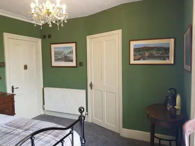 a bedroom with green walls and a bed and a chandelier at Afallon Townhouse in Dolgellau