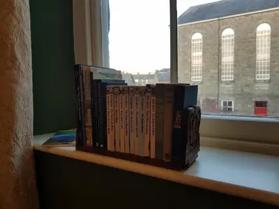 a row of books sitting on a shelf next to a window at Afallon Townhouse in Dolgellau