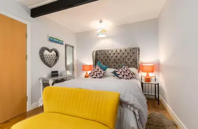 a bedroom with a bed and a yellow chair at No 31 Promenade APARTMENT by the sea in Aberystwyth
