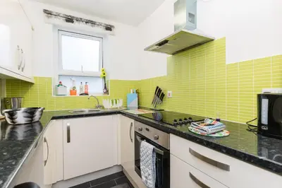 a kitchen with white cabinets and green tiles at No 31 Promenade APARTMENT by the sea in Aberystwyth