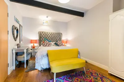 a bedroom with a bed with a yellow chair and a desk at No 31 Promenade APARTMENT by the sea in Aberystwyth