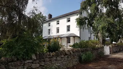 a white house with a stone wall at Upper Buckton B&B in Leintwardine