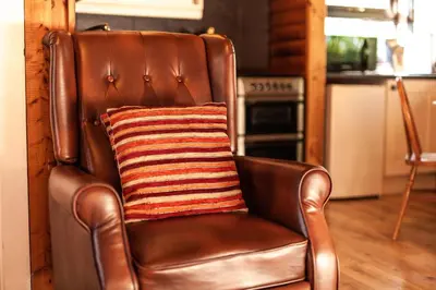 a brown leather chair with a striped pillow on it at Stunning Log Cabin with Garden in Snowdonia - Hosted by Seren Short Stays in Trawsfynydd