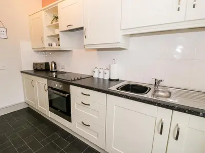 a kitchen with white cabinets and a sink at Rose Suite in Barmouth