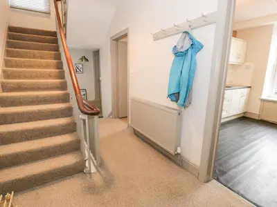 a hallway with stairs and a blue jacket hanging on a wall at Rose Suite in Barmouth