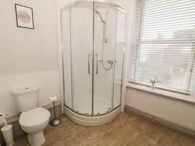 a bathroom with a shower with a toilet and a window at Rose Suite in Barmouth