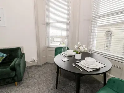 a dining room with a table and green chairs at Emerald Suite in Barmouth