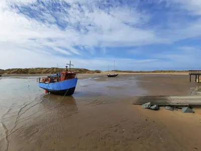 a blue boat sitting in the sand on the beach at Emerald Suite in Barmouth