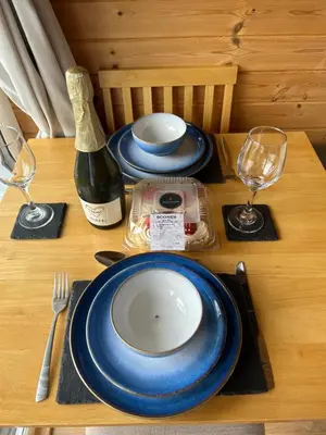 a table with blue and white plates and a bottle of wine at Forester's Retreat Glamping - Cambrian View- Vaccinated dogs over the age of 2 are accepted in Aberystwyth