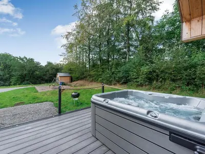 a hot tub on a deck with a backyard at Dwrgi - Uk32923 in Cwrt-newydd