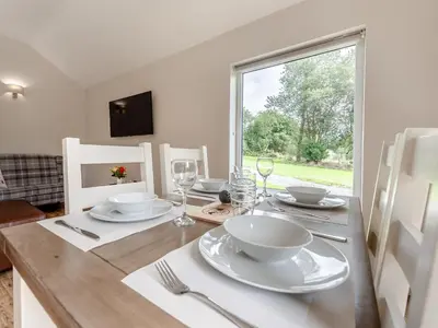 a dining room table with plates and glasses and a window at Dwrgi - Uk32923 in Cwrt-newydd