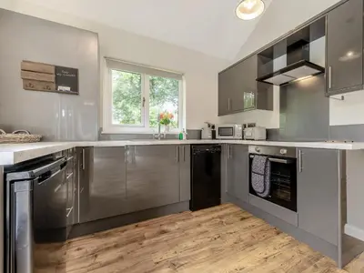 a large kitchen with stainless steel appliances and wood floors at Dwrgi - Uk32923 in Cwrt-newydd