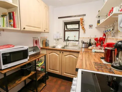 a kitchen with wooden cabinets and a microwave at The Wheelhouse at Dudgeley Mill in Church Stretton