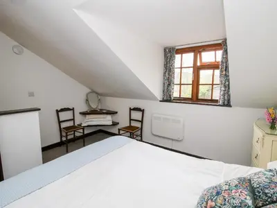 a bedroom with a white bed and two chairs at The Wheelhouse at Dudgeley Mill in Church Stretton