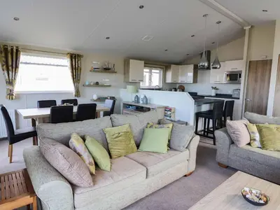 a living room with a couch and a kitchen at The Potting Shed in New Quay