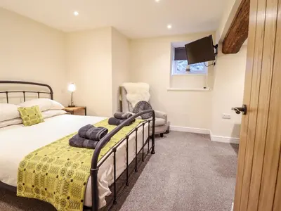 a bedroom with a bed and a chair and a tv at Hen Dy Bryn Mawndy in Corwen