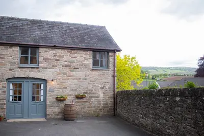 a brick house with a blue door and a stone wall at The Old Cider House in Hay-on-Wye