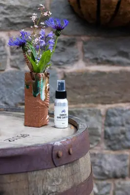 a vase of flowers on a barrel with a bottle of medicine at The Old Cider House in Hay-on-Wye