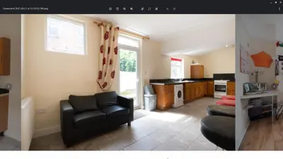 a living room with a black couch and a kitchen at 52 Cambrian St in Aberystwyth