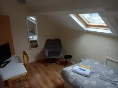 a bedroom with a bed and a chair and a window at 52 Cambrian St in Aberystwyth