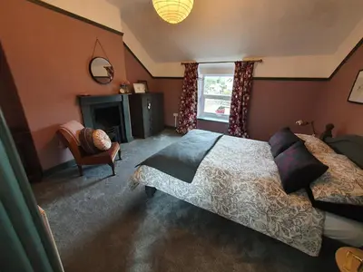 a bedroom with a bed and a chair and a fireplace at Llangollen 1-Bed Cottage Sleeps 2 with Parking in Llangollen